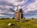 Öland i fokus – Kalmar med omnejd Väderkvarn i öppet landskap under molnig himmel.